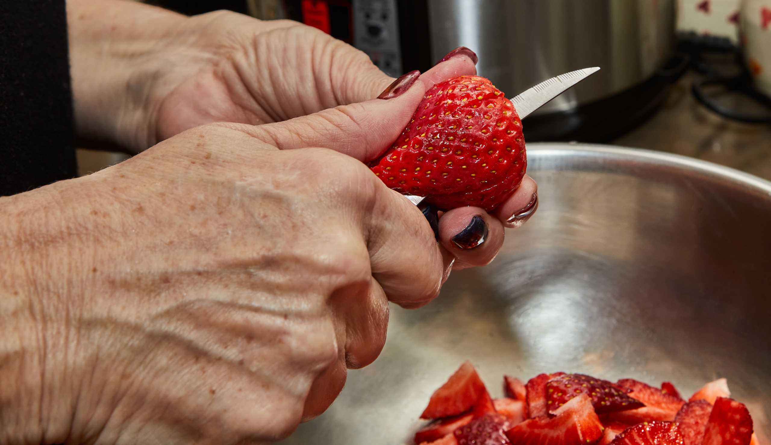 Chef cuts strawberries for dessert in the home kitchen.